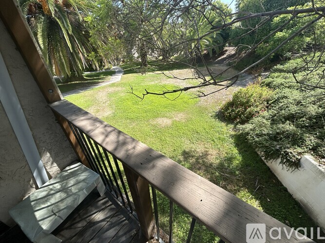 A balcony overlooks a green lawn and trees.