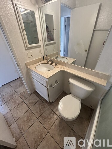 A bathroom with a toilet, sink, and mirror.