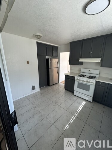 A kitchen with black cabinets and a white stove top oven.