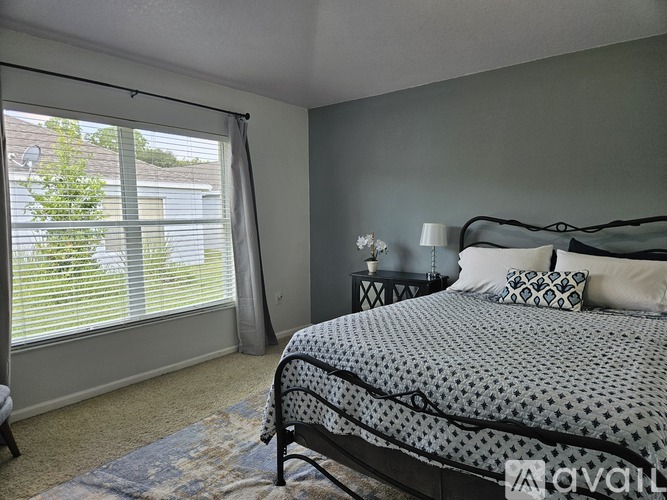 A bedroom with a bed, nightstands, and a window with blinds.
