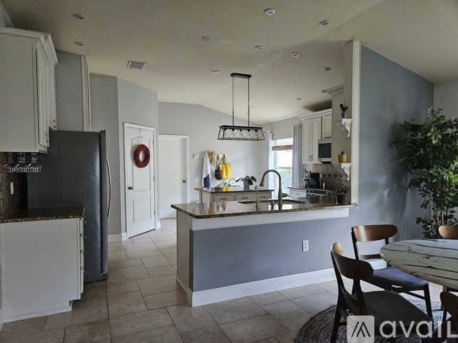 A kitchen with a black refrigerator and a dining table with chairs.