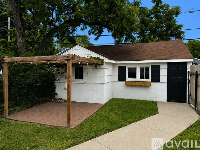 A white house with a black door and a brown roof.
