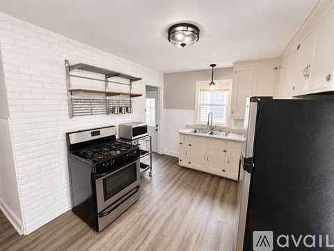 A kitchen with a black stove top oven and white brick wall.