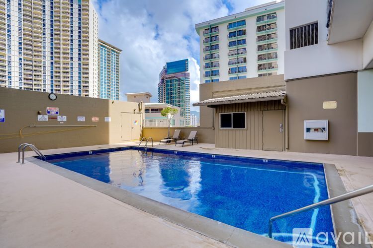 A swimming pool in a sunny outdoor area with a building in the background.