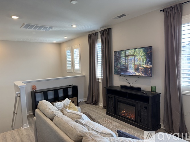 A living room with a grey couch and a fireplace.