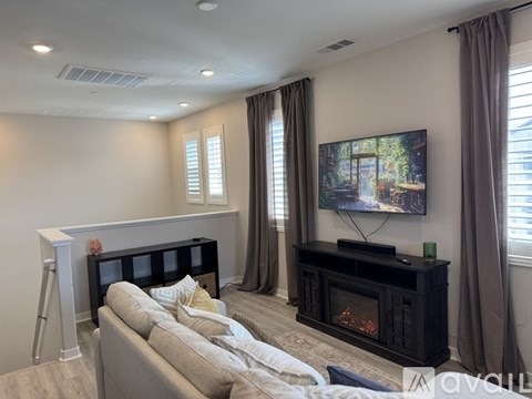 A living room with a grey couch and a fireplace.