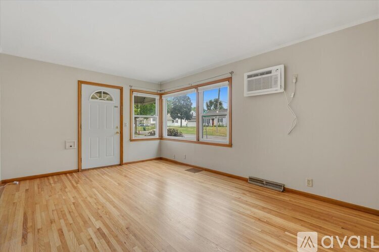 A room with wooden flooring and a window overlooking a street.