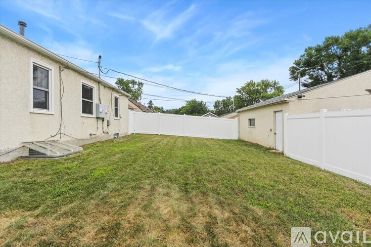 A backyard with a white fence and a grassy area.