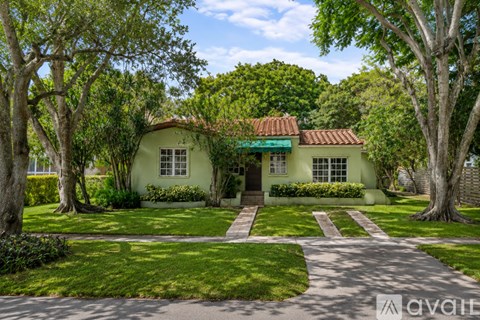 A house with a green lawn and trees around it.