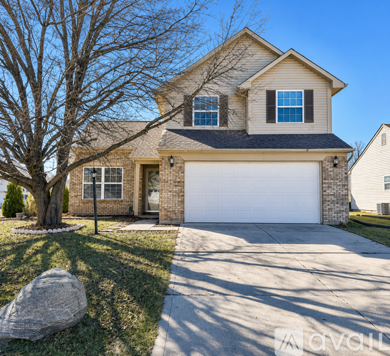 A house with a white garage door and a tree in front.