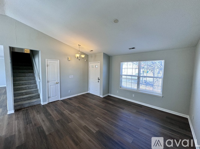 A room with wooden floors and a window with a view of trees outside.