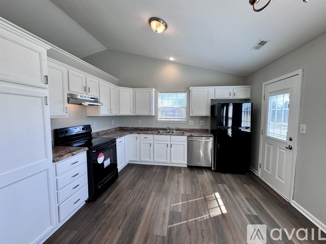 A kitchen with black appliances and white cabinets.