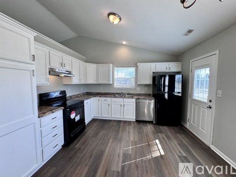 A kitchen with black appliances and white cabinets.