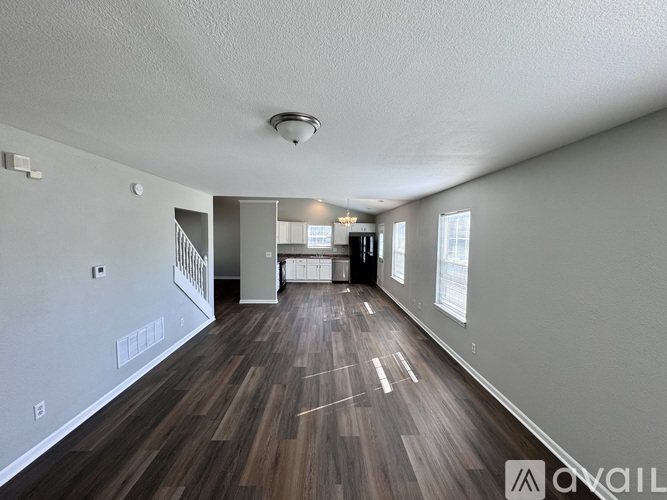 A spacious room with wooden flooring and white walls.