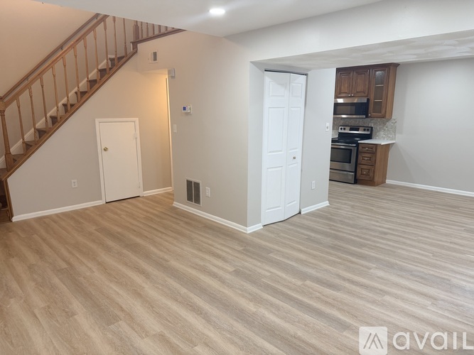 A living room with a staircase and a kitchen area in the background.