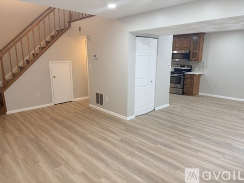 A living room with a staircase and a kitchen area in the background.