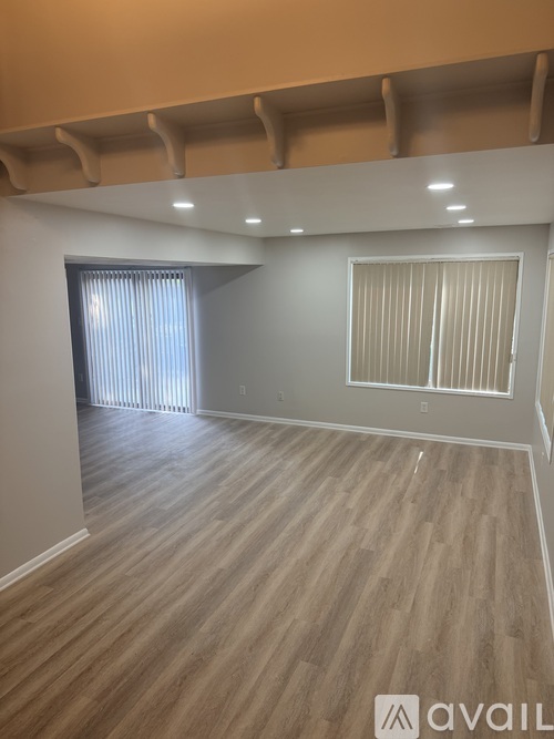 A room with wooden flooring and a window with blinds.
