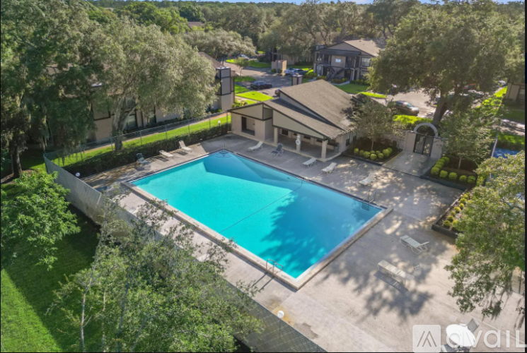 A large swimming pool surrounded by a concrete patio and a grassy area with trees.