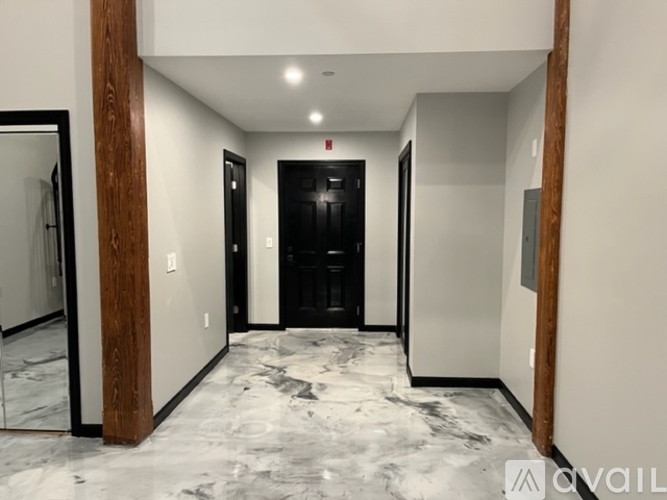 A hallway with a black door and a marble floor.