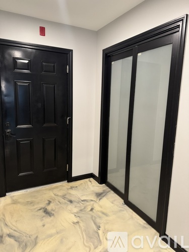 A black door with a glass panel is on the left and a black door with a glass panel is on the right.