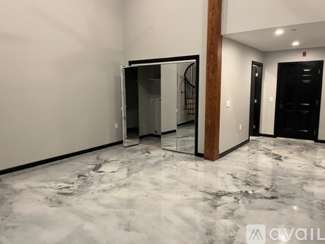 A marble floor in a room with a wooden column and a black door.