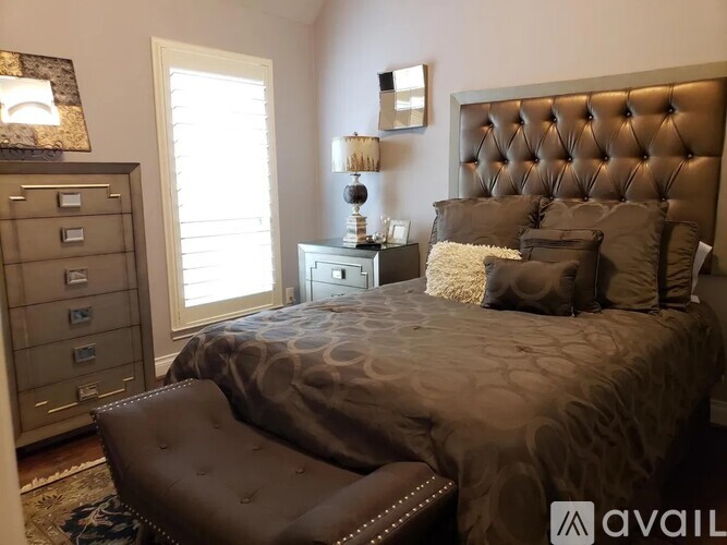 A bedroom with a large bed and a brown tufted headboard.