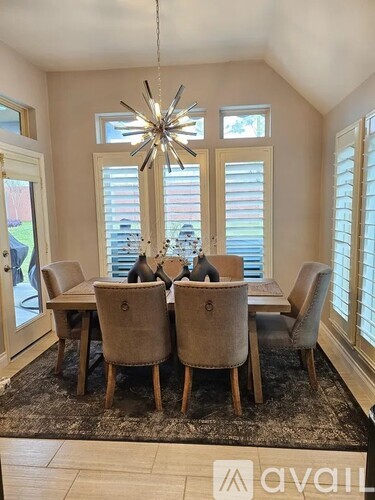A dining room with a table set for four and a chandelier hanging from the ceiling.