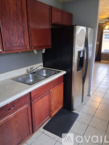 A kitchen with wooden cabinets and a black fridge.