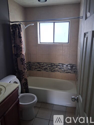 A bathroom with a toilet, tub, and window.