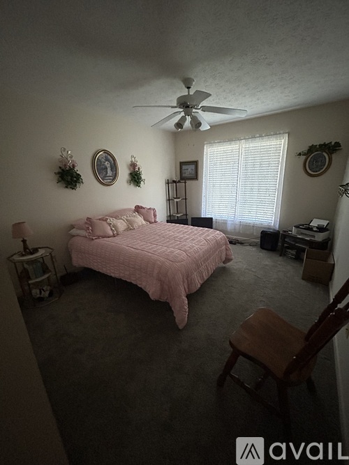 A bedroom with a pink bed and a ceiling fan.