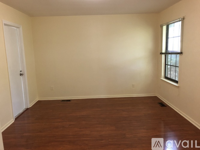 Empty room with wooden floors and a window on the right side.