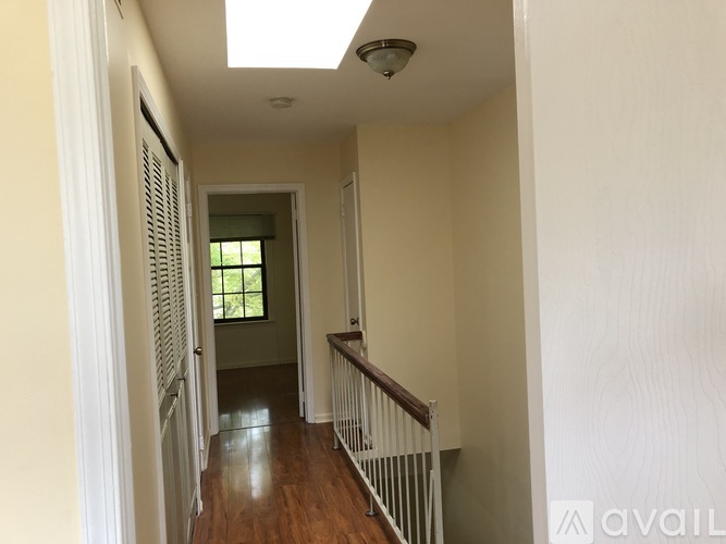 A hallway with a wooden floor and white walls.