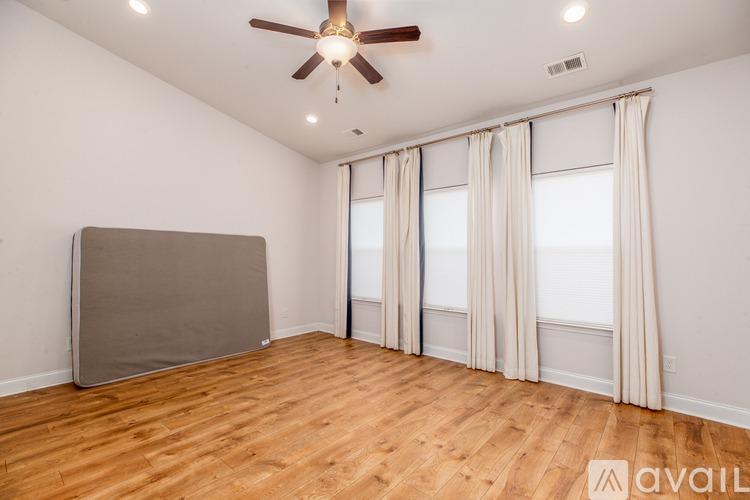 A room with a ceiling fan and wooden flooring.