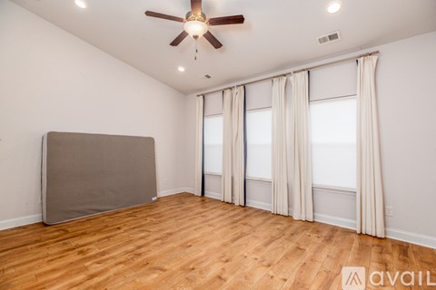 A room with a ceiling fan and wooden flooring.