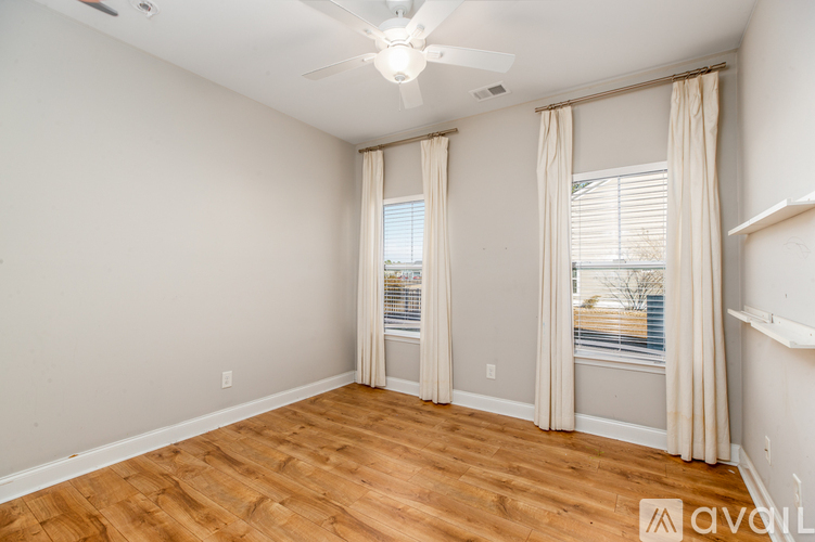 A room with a ceiling fan and sliding glass doors.
