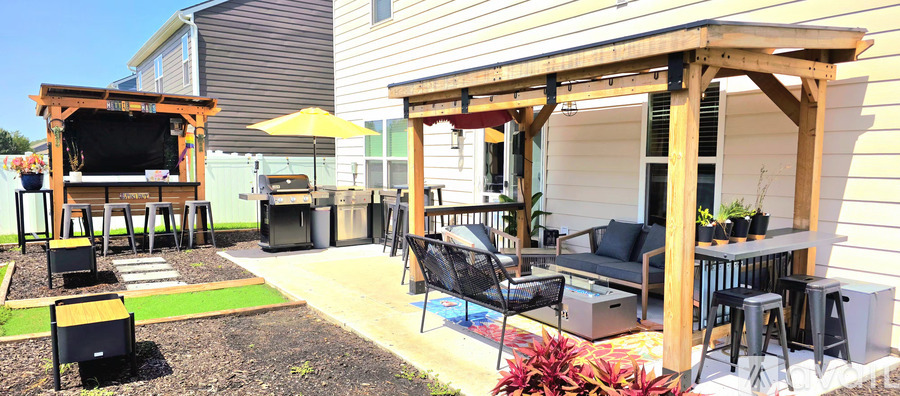 A backyard with a wooden pergola and a black grill.