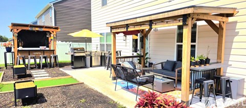 A backyard with a wooden pergola and a black grill.