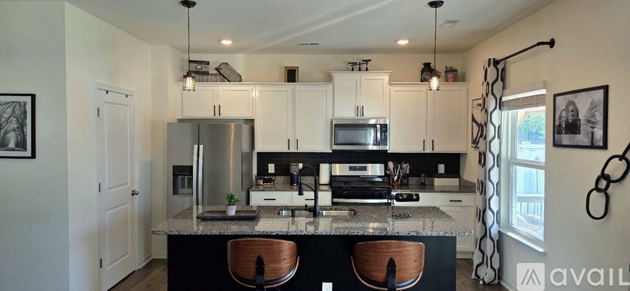 A kitchen with white cabinets and a black island.