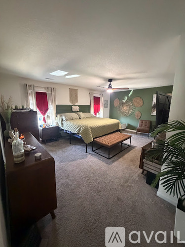 A bedroom with a bed, a bedside table, and a ceiling fan.