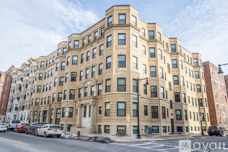 A large, beige building with many windows is situated on a street corner.