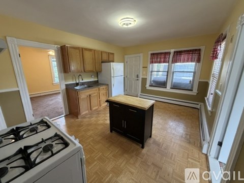 A kitchen with a white gas stove and wooden flooring.