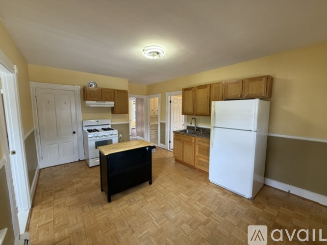 A kitchen with a white refrigerator, wooden cabinets, and a black table.