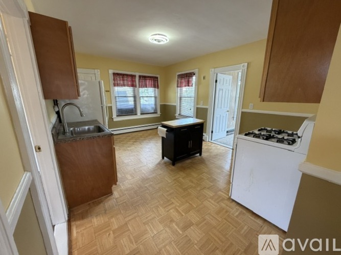 A kitchen with a white stove and wooden flooring.