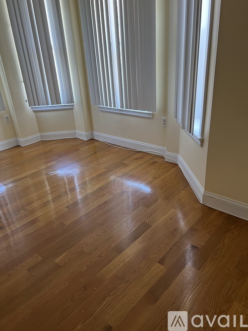 A room with wooden flooring and striped blinds.