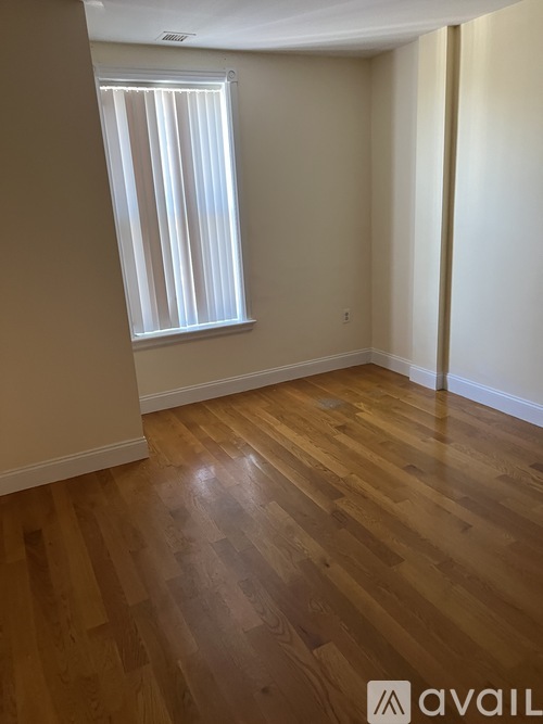 A room with wooden flooring and a window with blinds.