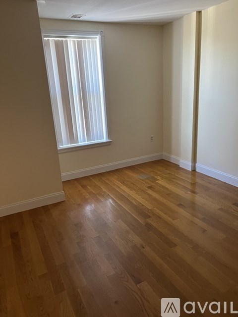 A room with wooden flooring and a window with blinds.