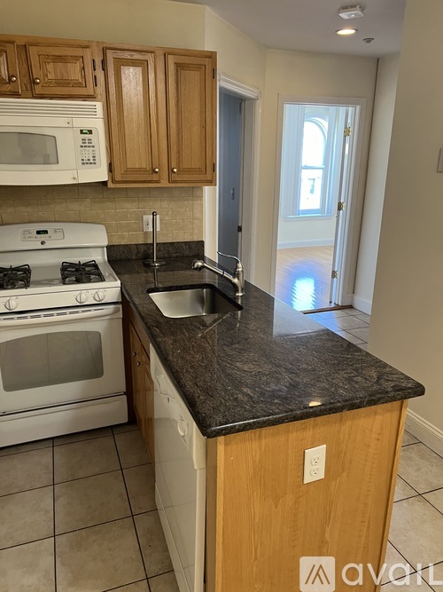A kitchen with a white stove and a black counter top.