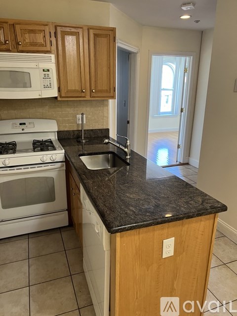 A kitchen with a white stove and a black counter top.