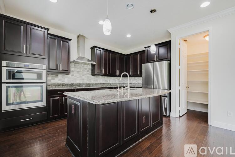 A kitchen with dark wood cabinets and a marble island.