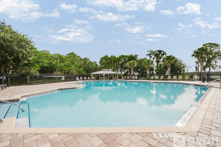 A large outdoor swimming pool surrounded by trees and a fence.
